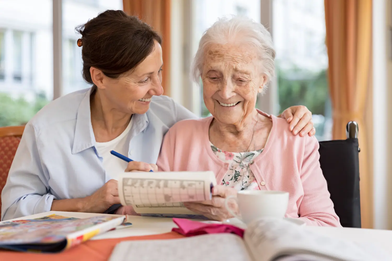 Glückliche Seniorin im Rollstuhl mit Pflegekraft