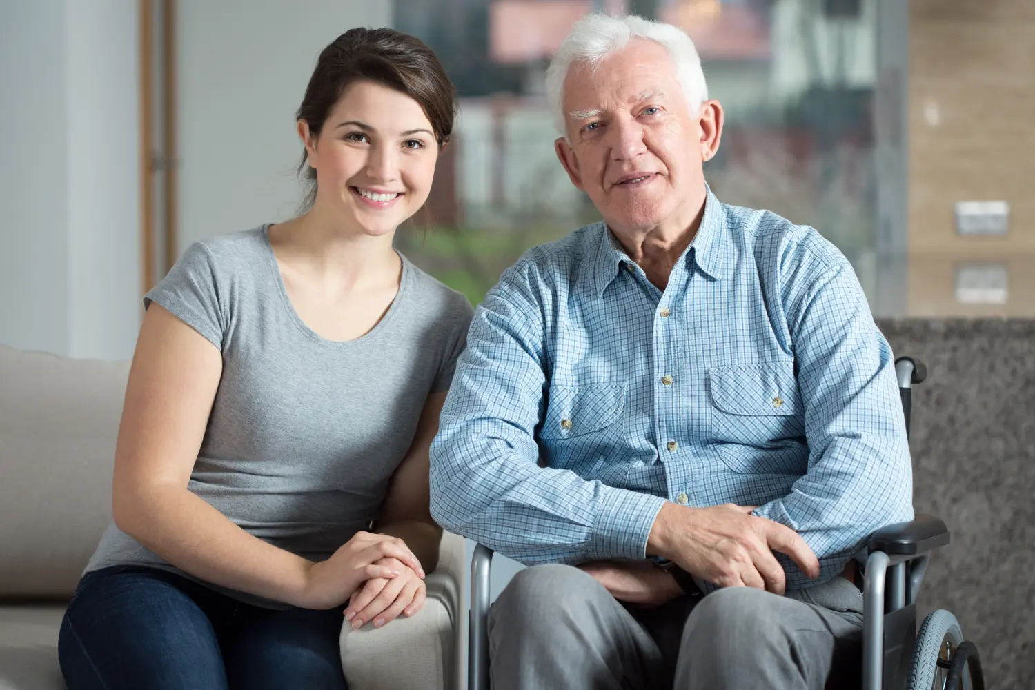 Glückliche Seniorin im Rollstuhl mit Pflegekraft
